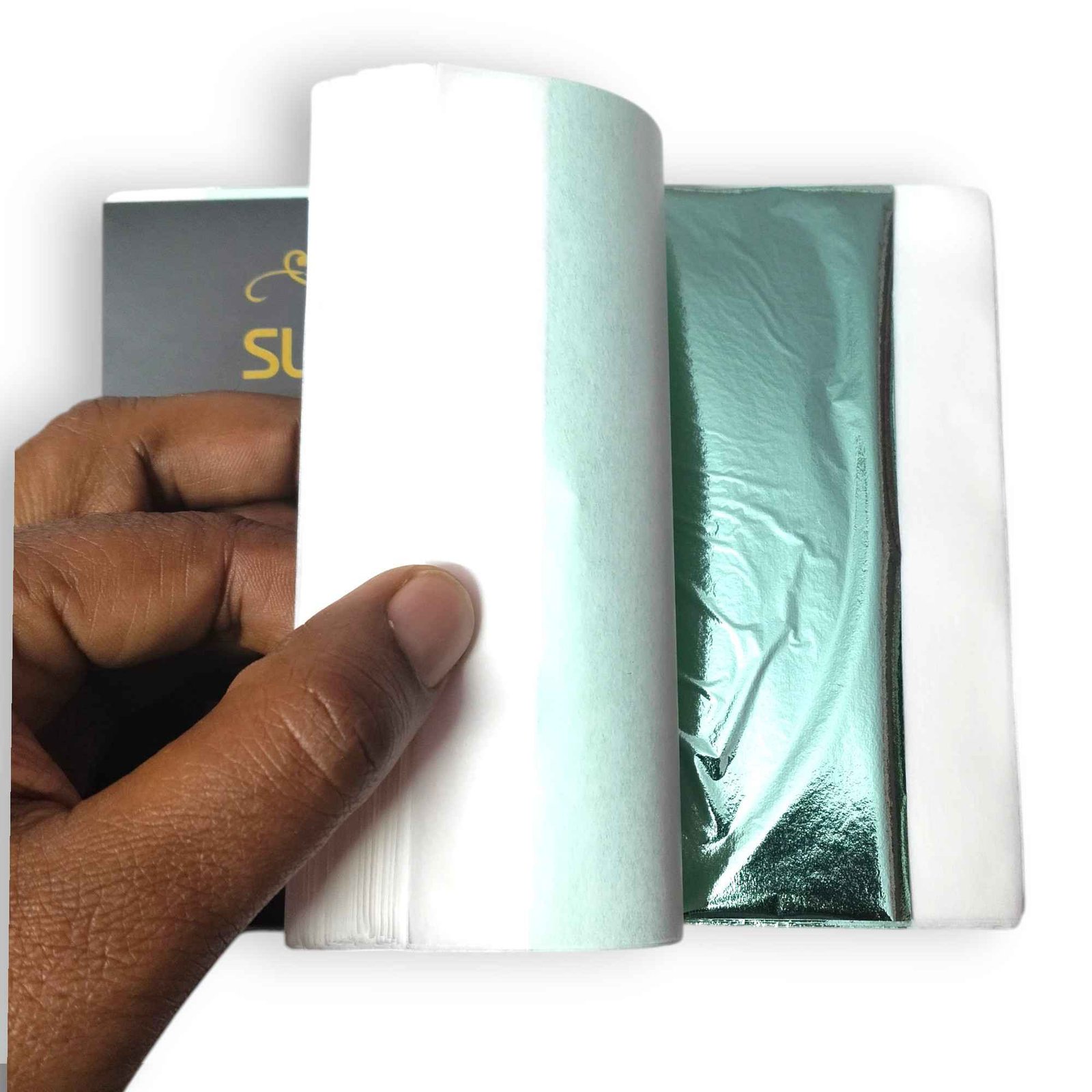 Light green gold leaf foil sheet being lifted from tissue-interleaved booklet