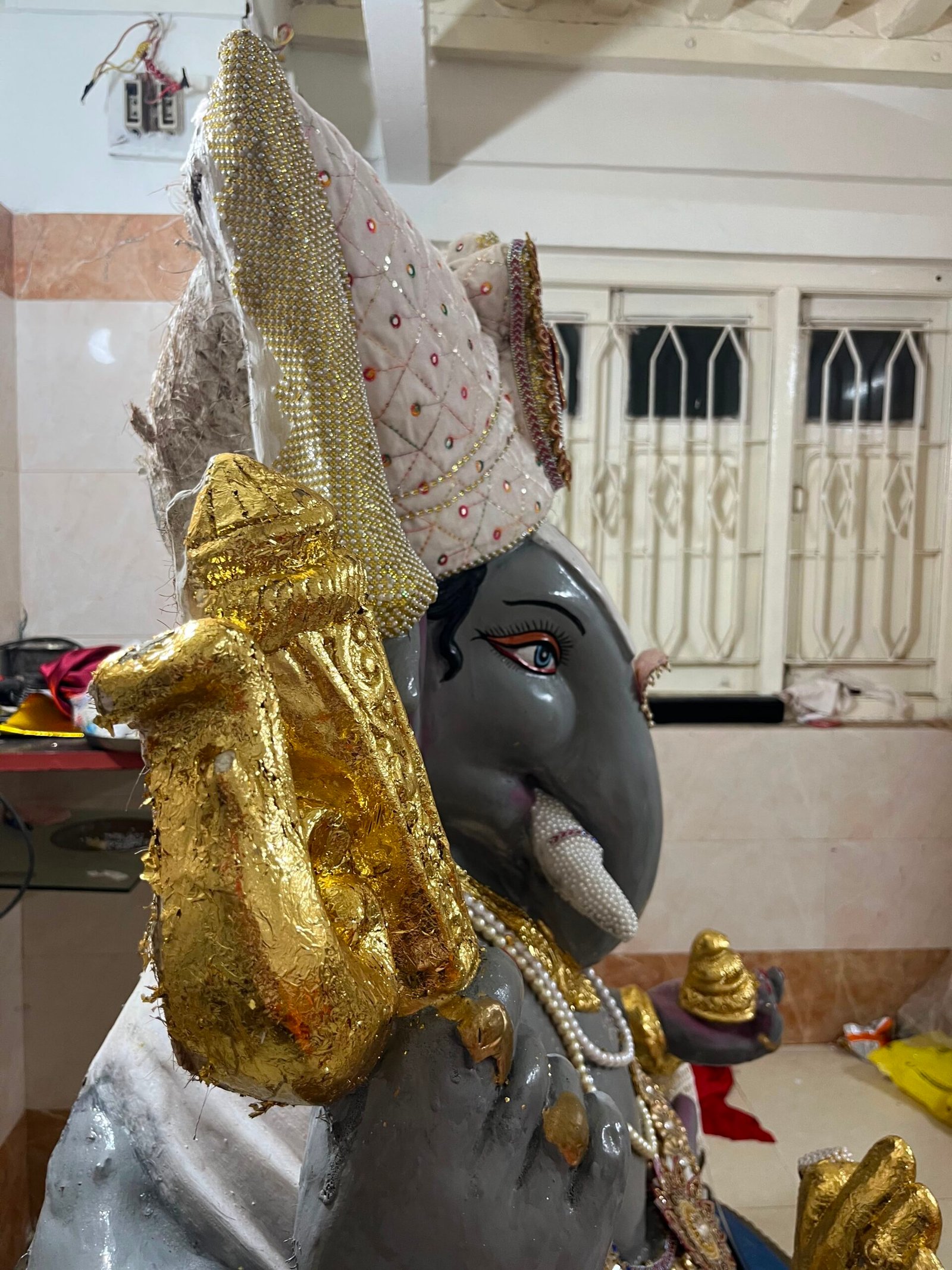 Ganesh murti ke mukut aur aayudh par gold leaf side view
