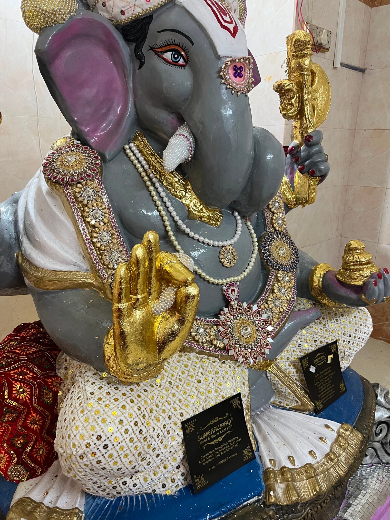 Gold leaf hatheli aur kalash ka close up Ganesh murti