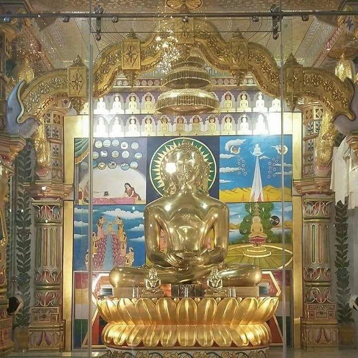 Golden Jain murti seated under a fully gold leafed toran arch in a mandir