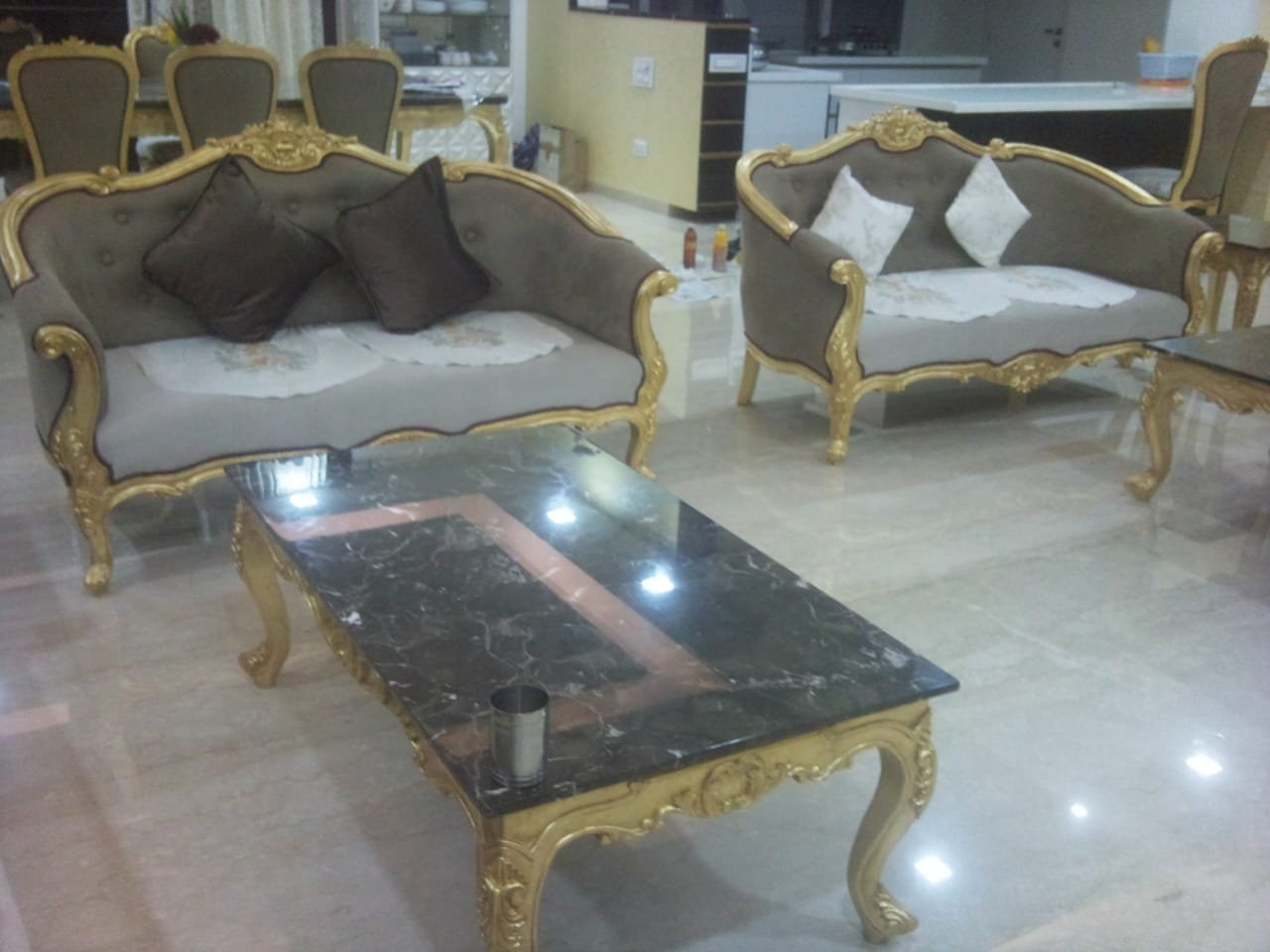 Gold leafed sofa set and marble top coffee table installed in a living room by Sumera Warq
