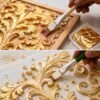 Craftsman using Sumera Warq gilding brush to apply adhesive glue and gold leaf on carved wooden panel