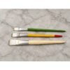 Flat lay of three gold leafing kalam brushes in small, medium and large sizes on marble background